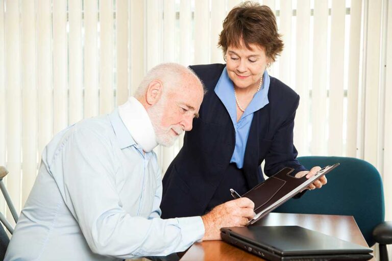 Two people discussing paperwork after a minor car accident on a residential street in winter.